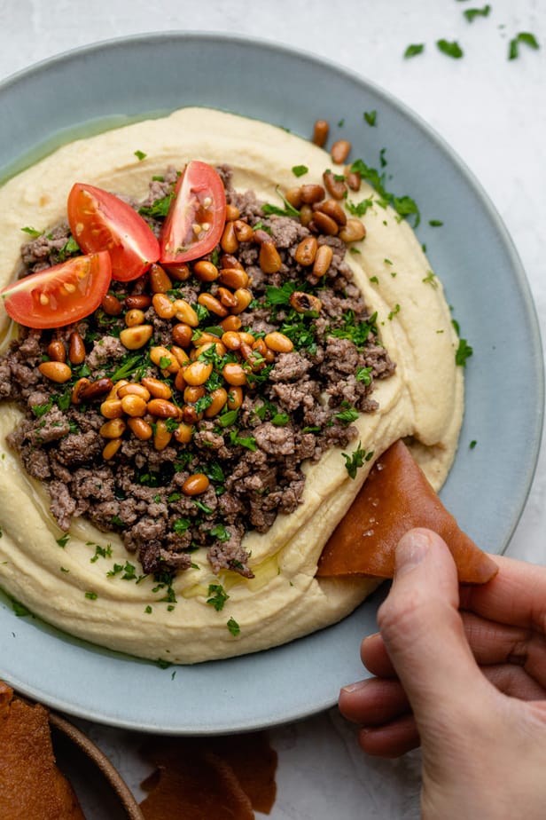 Chip being dipped into Hummus with Ground Beef 