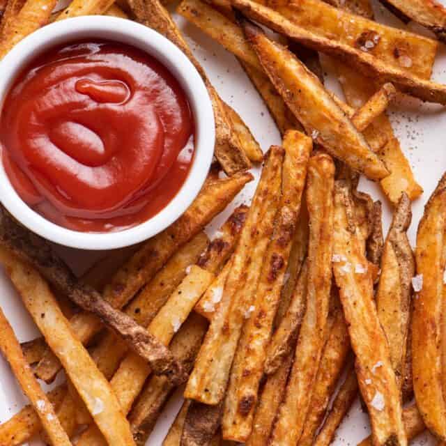 A pile of Crispy oven baked french fries with ketchup in the middle