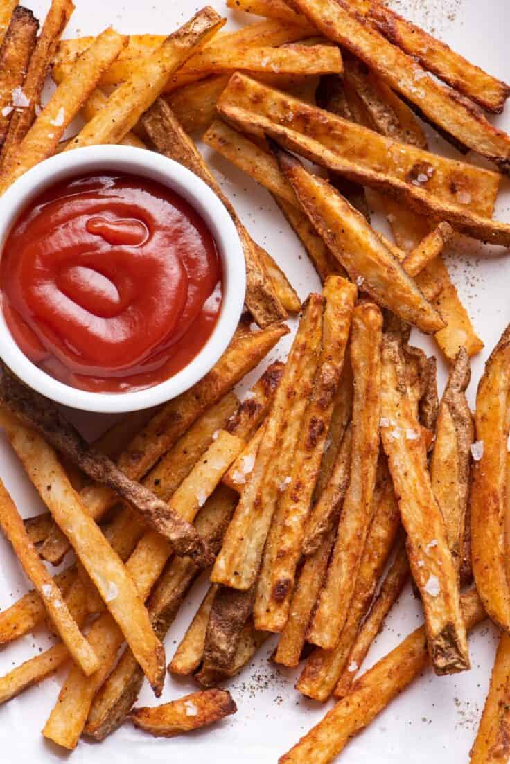 A pile of Crispy oven baked french fries with ketchup in the middle