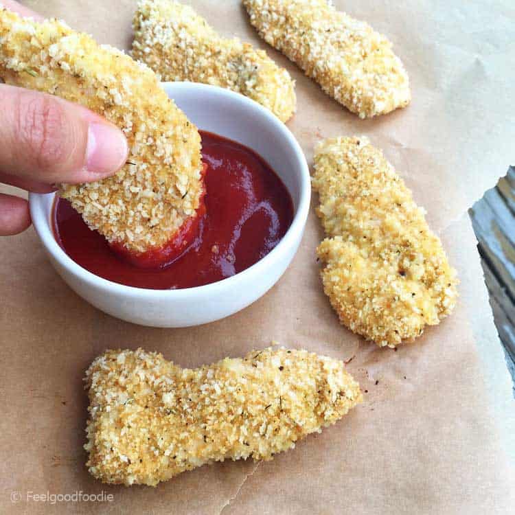 chicken tender being dipped in ketchup