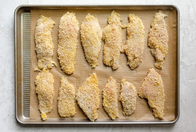 Chicken tenders breaded with egg and breadcrumbs on a baking dish