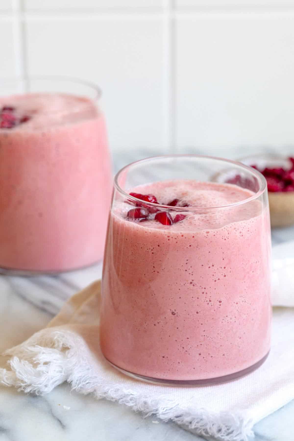 Two clear glass cups of pomegranate smoothies