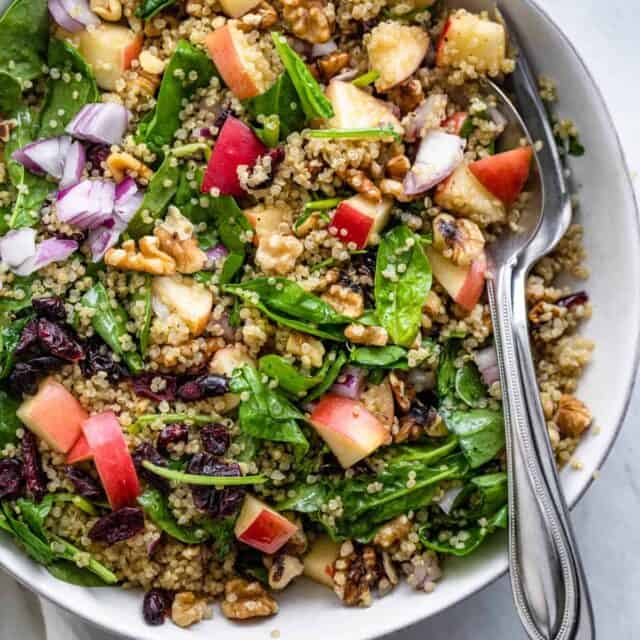 Walnut apple quinoa salad serve in a large bowl with utensils