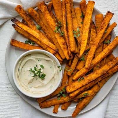 Round plate of fries with mayo dipping sauce for the butternut squash sticks