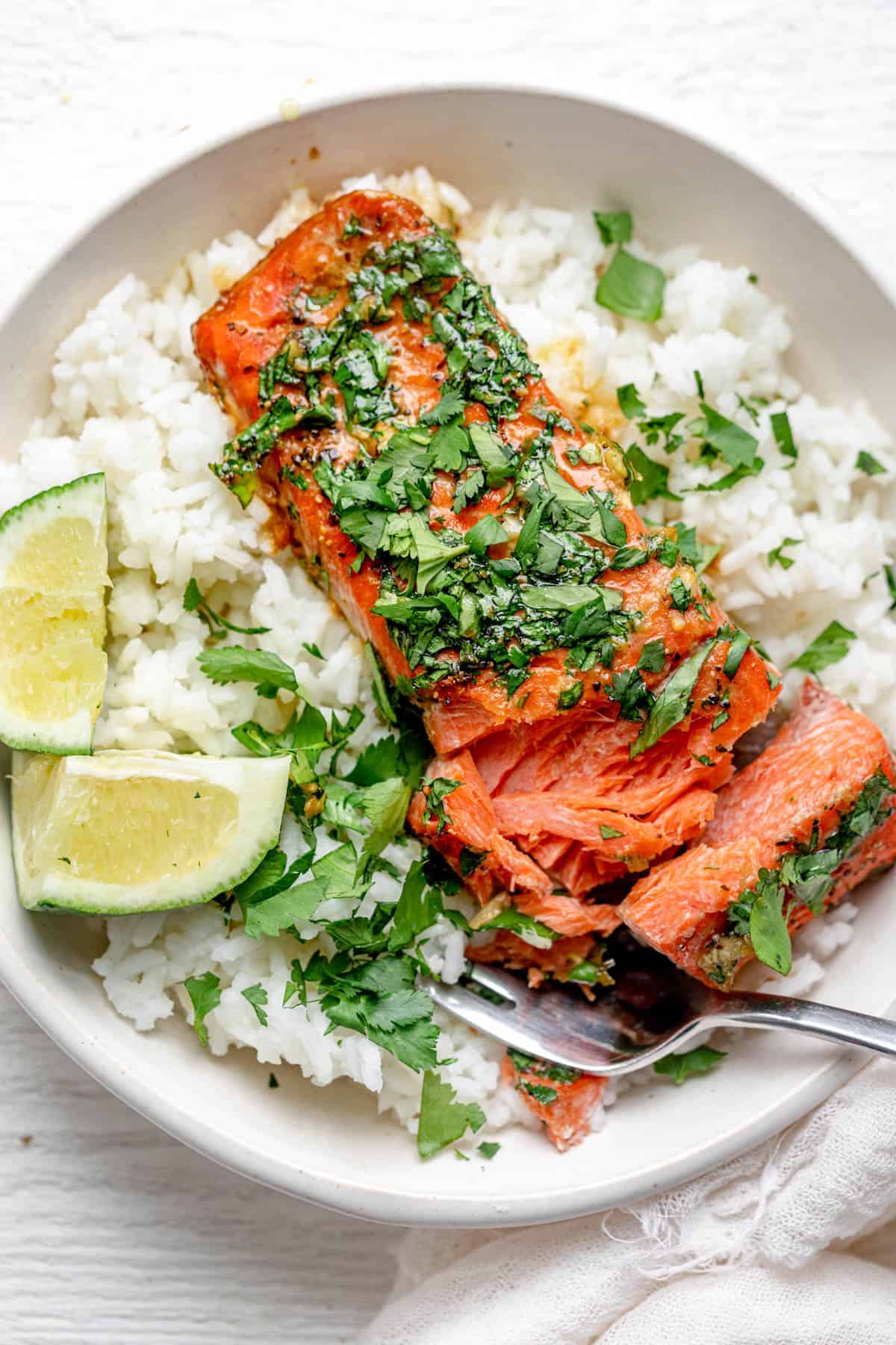 Cutting into the salmon to show how flaky it is, topped with lots of fresh cilantro over rice
