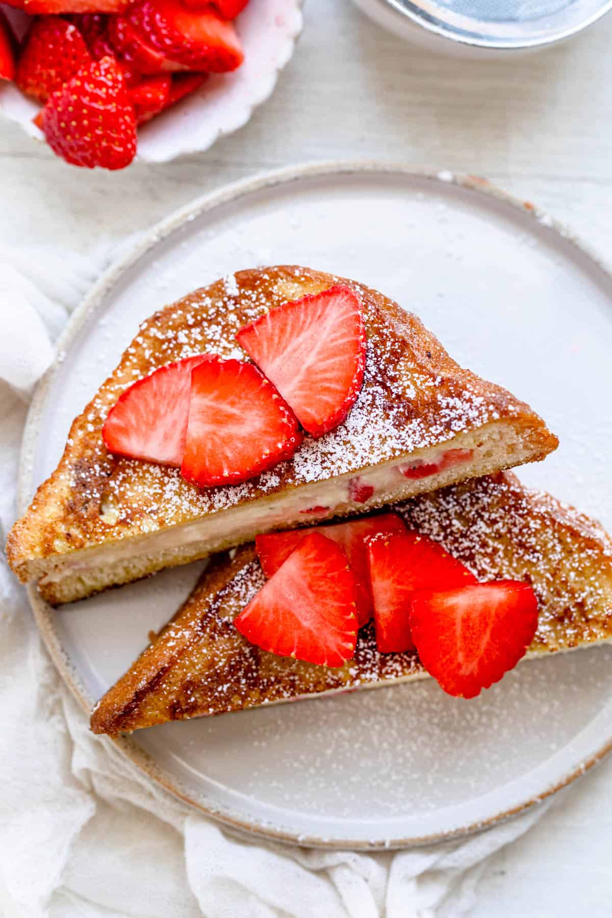 One stuffed french toast, cut in half topped with sliced strawberries and powdered sugar