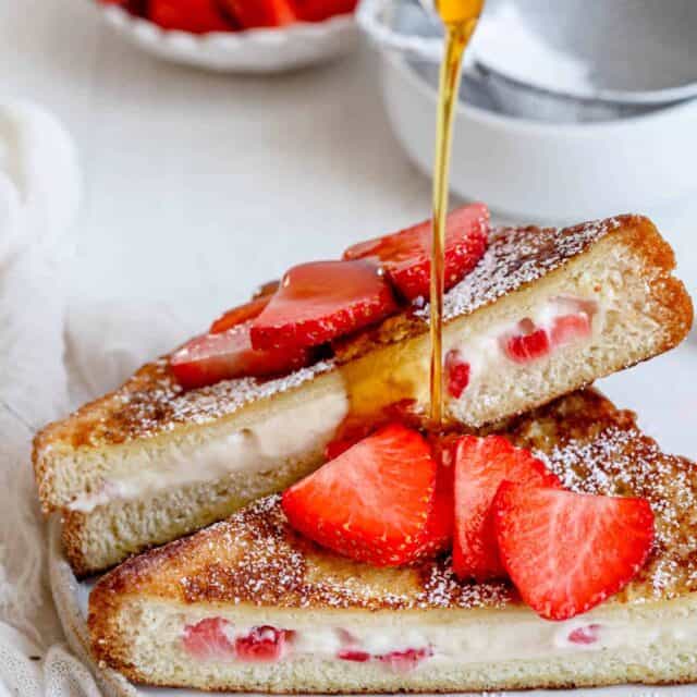 Angle shot of stuffed french toast showing the cream cheese filling with maple syrup pouring on top