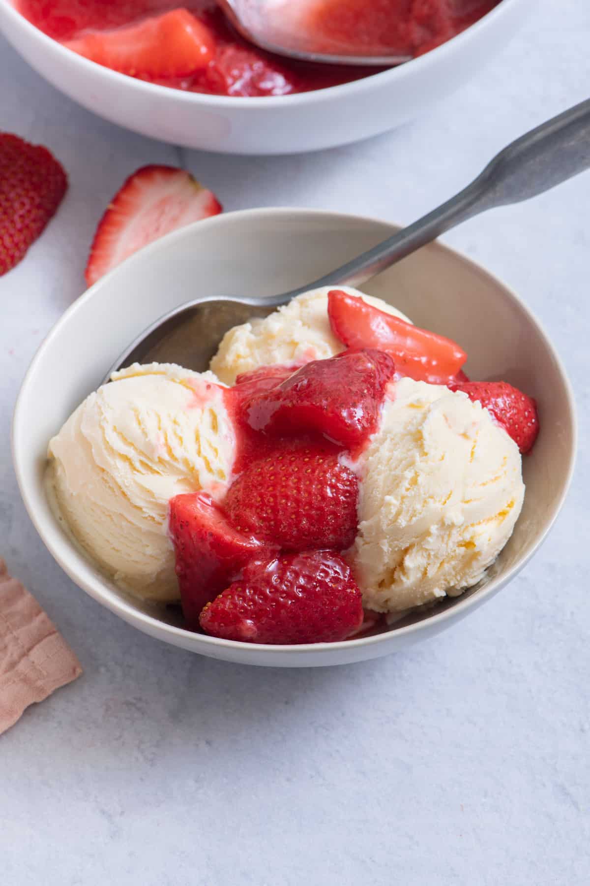 Bowl with 3 scoops of ice cream topped with strawberry sauce.