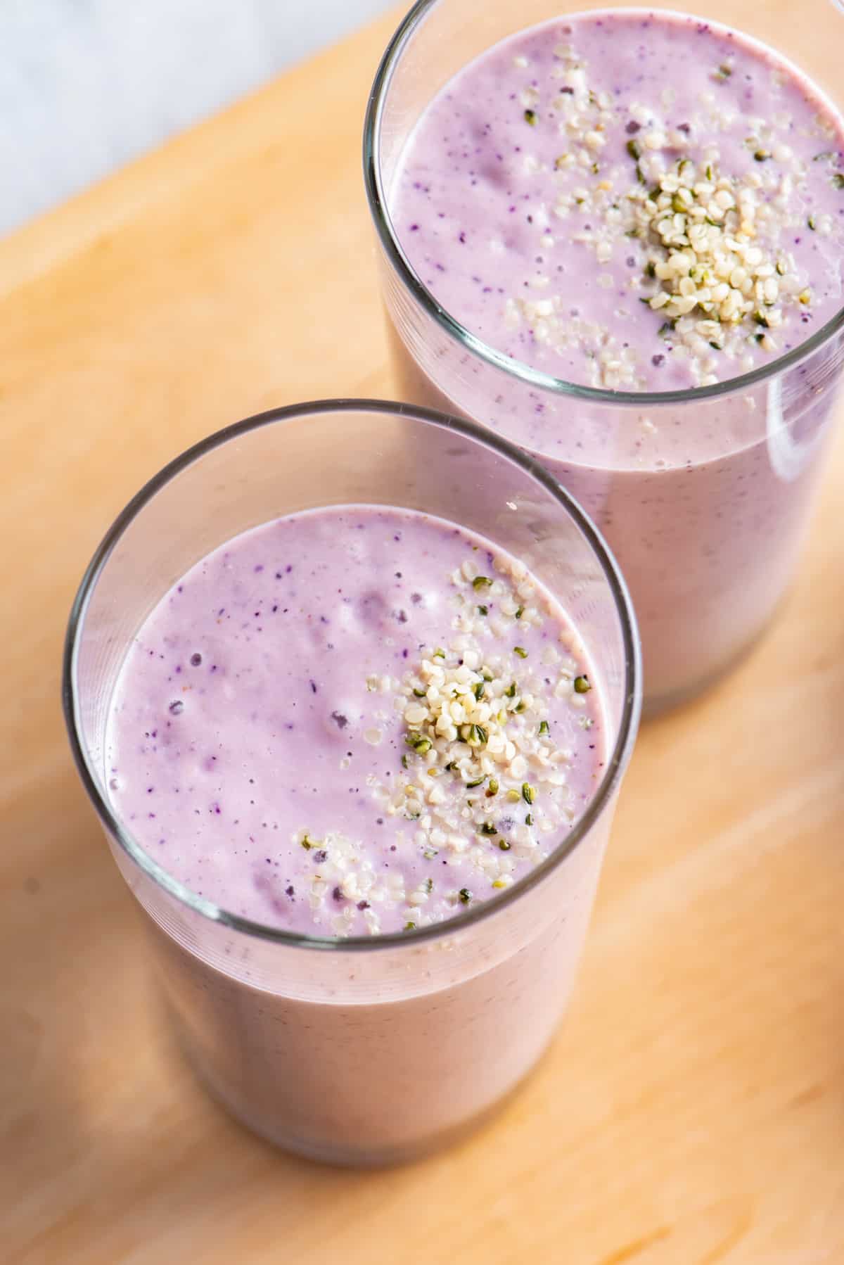 Top view of two glasses of banana berry smoothies with hemp seeds sprinkled on top