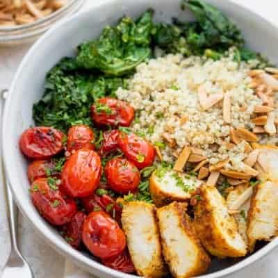 Large bowl of chicken and quinoa served with tomatoes, kale and toasted almonds