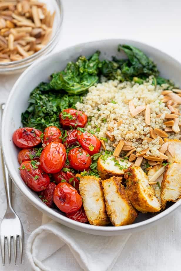 Large bowl of chicken and quinoa served with tomatoes, kale and toasted almonds