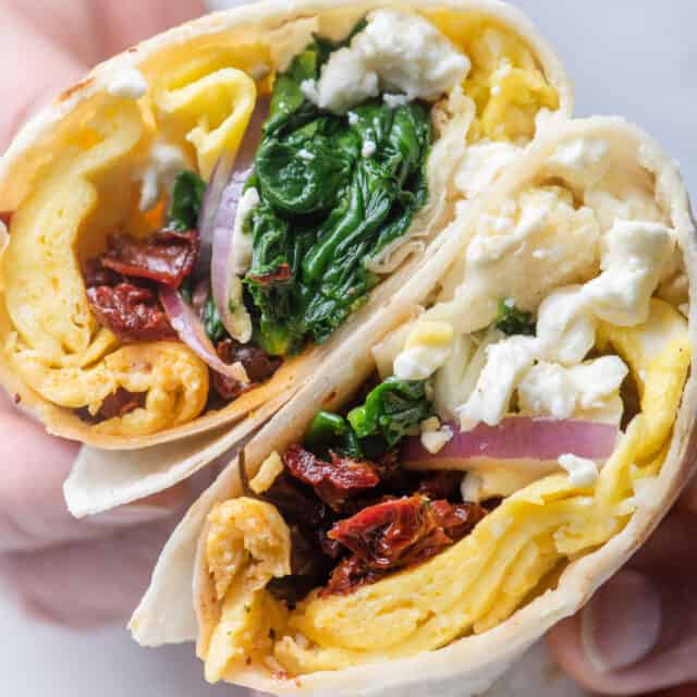 Handles holding two halves of mediterranean egg wrap to show what's inside the wrap