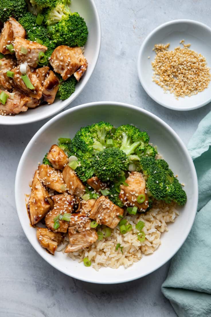 Chicken Teriyaki, Brown Rice and Broccoli in bowls with sesame seeds on the side