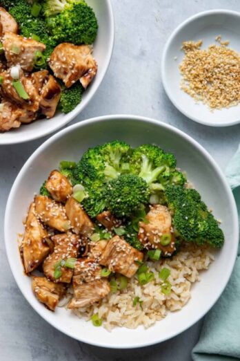 Chicken Teriyaki, Brown Rice and Broccoli in bowls with sesame seeds on the side