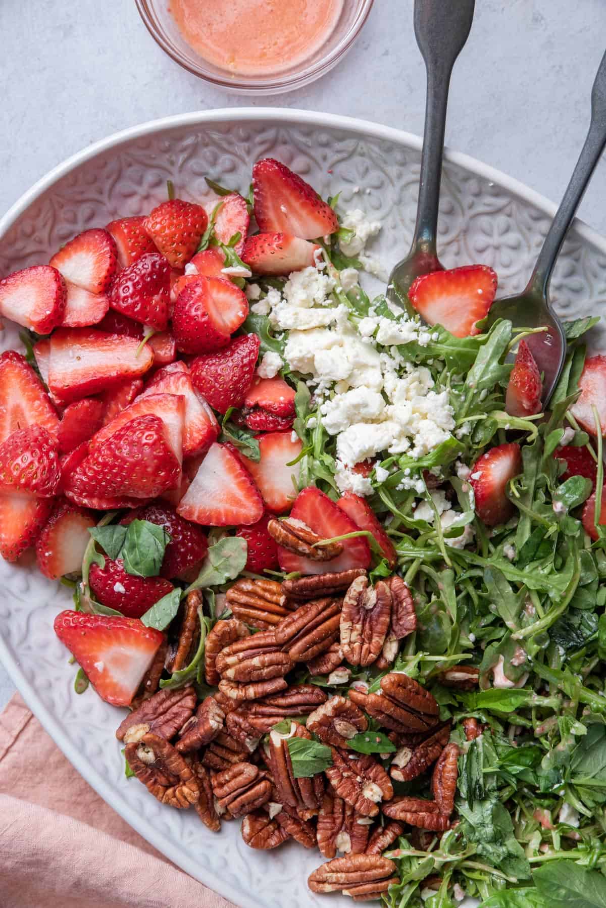 Close up shot of the strawberry arugula salad with fork and spoon for serving