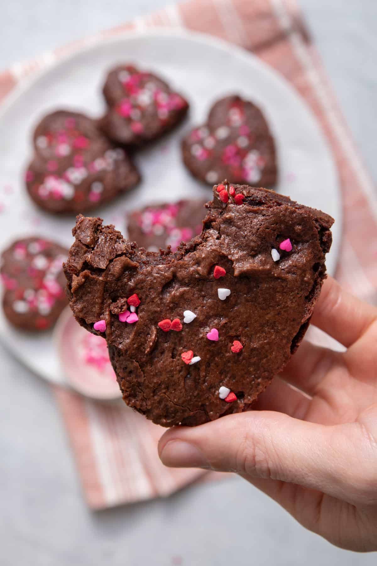 Hand holding chocolate fudgy brownies with bite taken out to show consistency