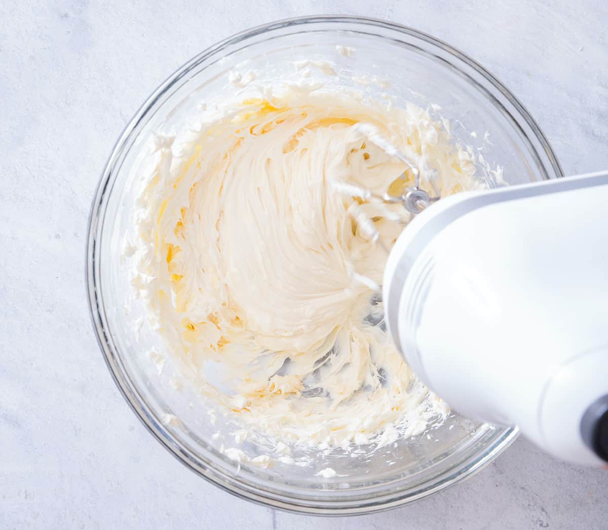 Bowl of the cream cheese frosting getting whisked