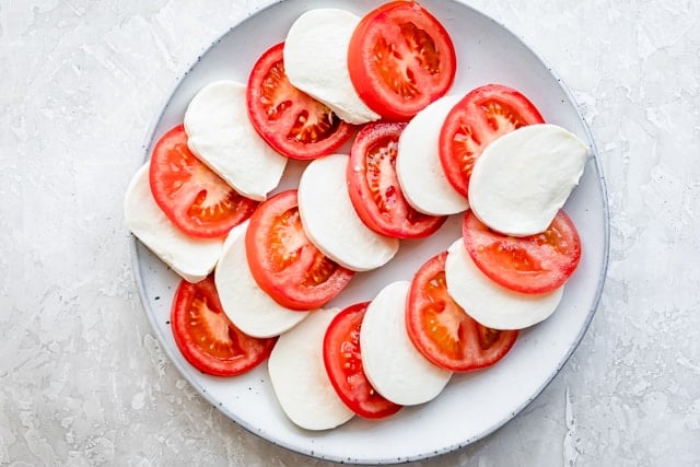 Alternating tomat and mozzarella slices on a serving platter