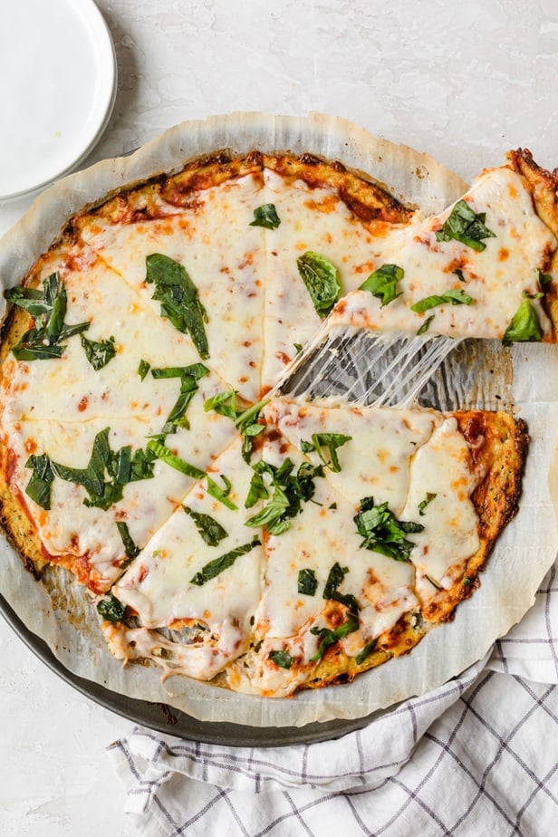 Cheesy slice of cauliflower pizza crust being served