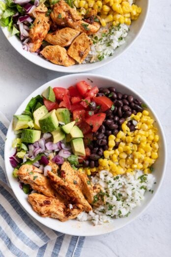 Two chicken burrito bowls with toppings