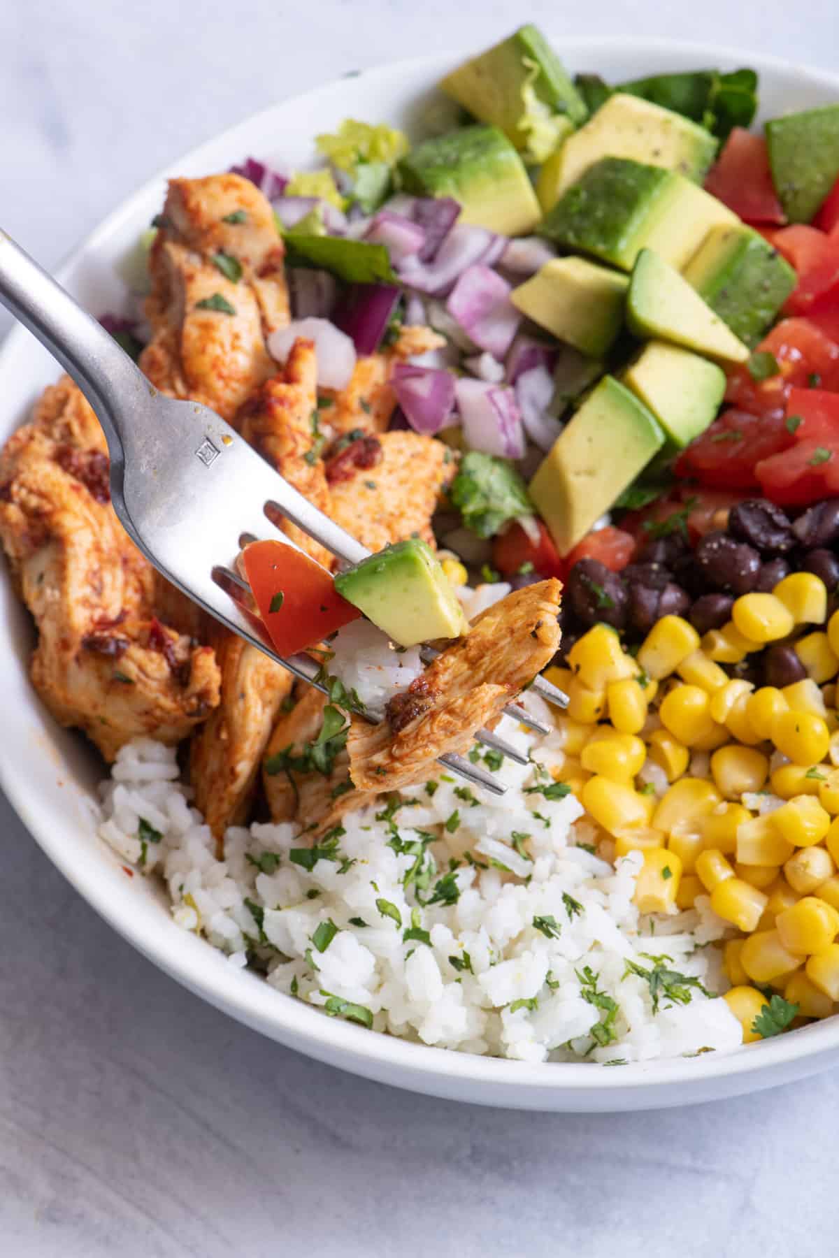 Fork grabbing bite from chicken burrito bowl