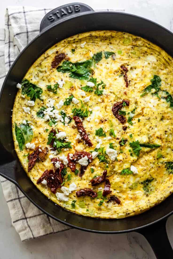 Mediterranean Frittata in a cast iron skillet topped with sundried tomatoes, feta cheese and parsley