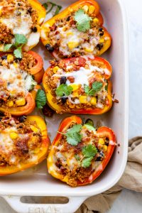White baking dish with quinoa stuffed peppers