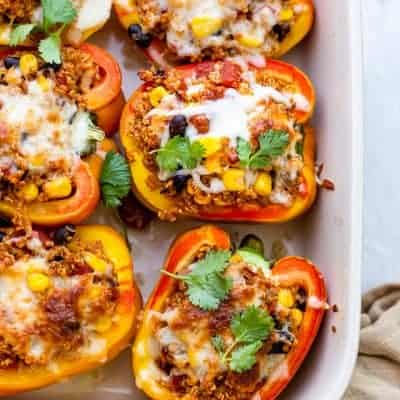 White baking dish with quinoa stuffed peppers