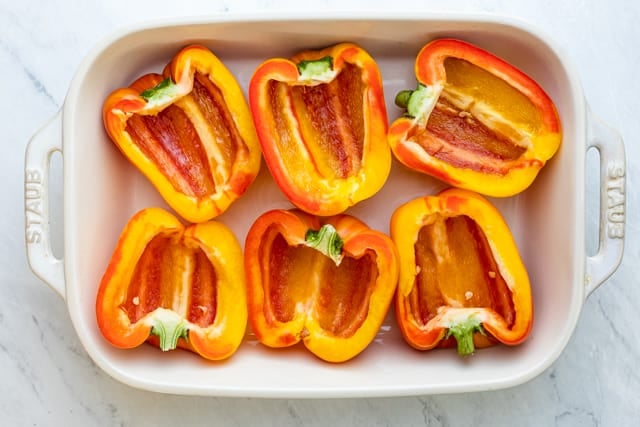 6 hallowed peppers halves on a white baking dish