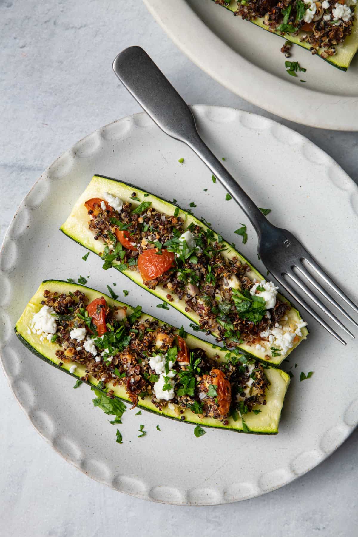 Plate with two quinoa stuffed zucchini boats and fork