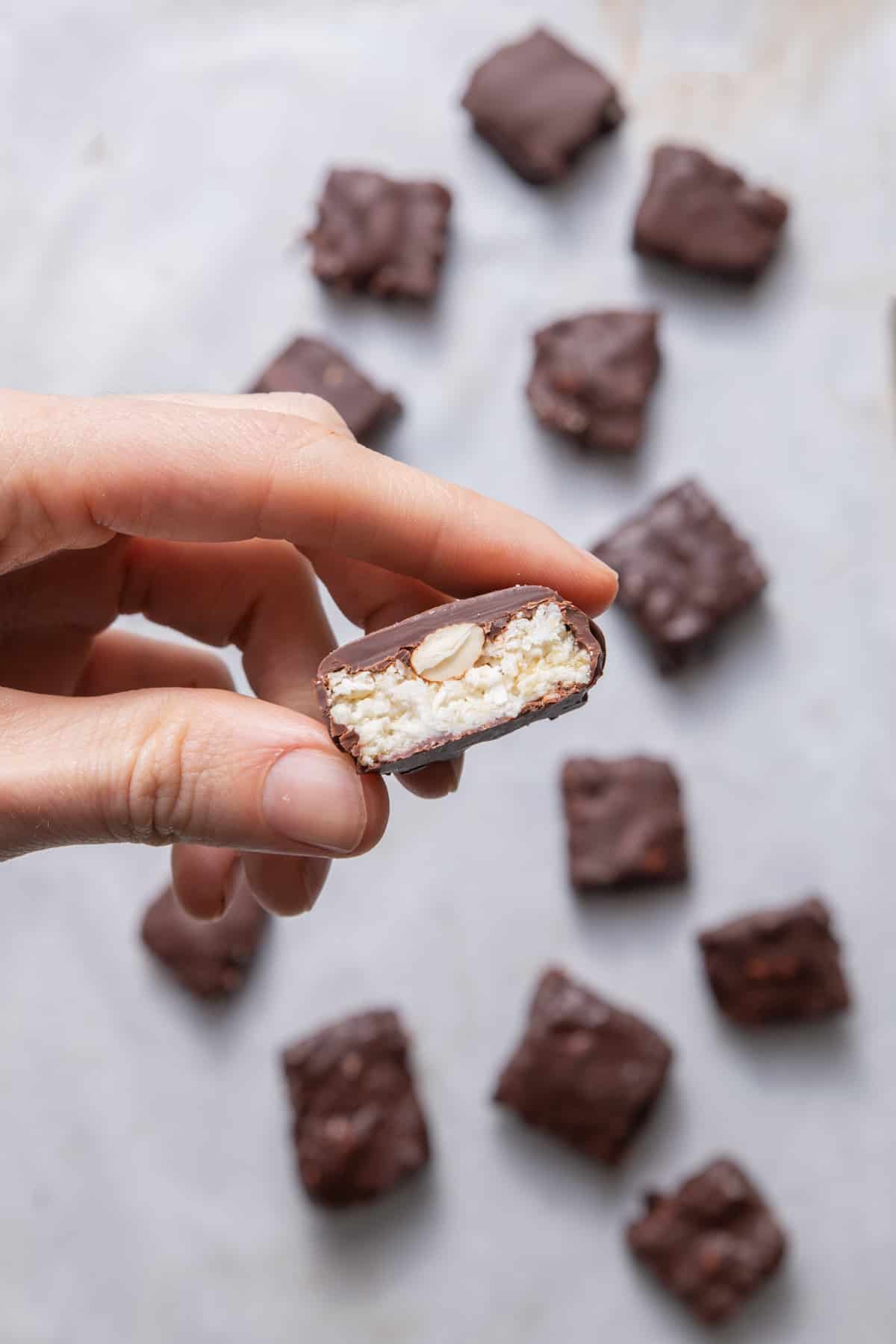 Hand holding up one almond joy bar that's cut in half