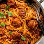 Large skillet of spaghetti and meatballs topped with basil