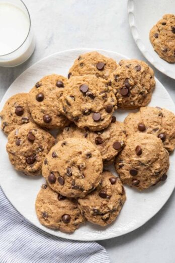 Plate of applesauce chocolate chip cookies with glass of milk next to them