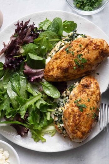 Spinach & Feta Stuffed Chicken served with mixed greens on white plate