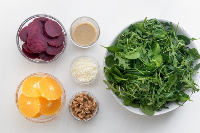 Ingredients to make the salad: arugula and spinach mix, beets, oranges, nuts, feta cheese and the homemade dressing