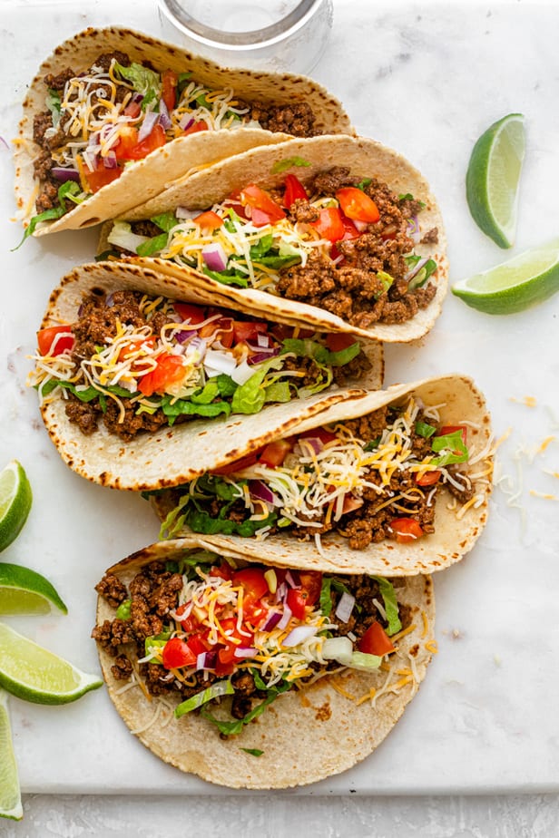 Ground beef tacos topped with lettuce, tomatoes, cheese and onions