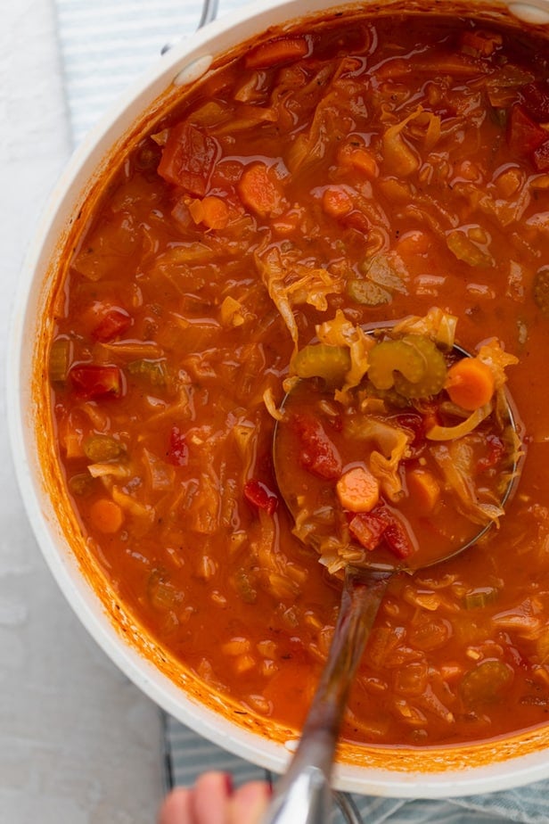 Large pot of the cabbage soup with a ladle side