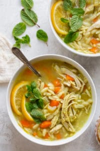 Large bowl of chicken lemon orzo soup garnished with mint