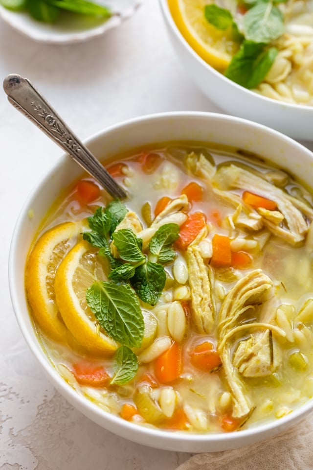 Close up shot of chicken lemon orzo soup with spoon inside