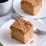 Two small plates of cinnamon coffee cake with coffee mug in background