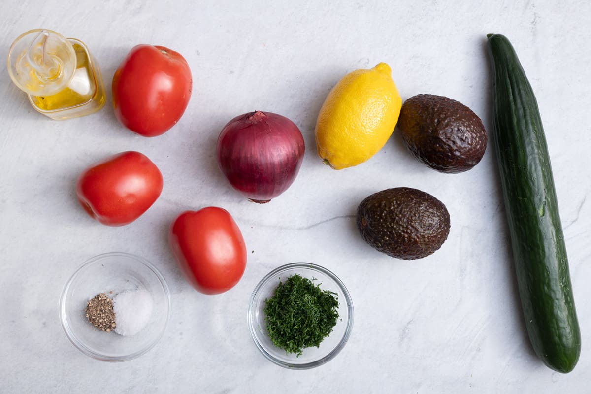 Ingredients to make the salad recipe: tomatoes, cucumber, avocado, red onions, salt, pepper, herbs, olive oil and lemon juice