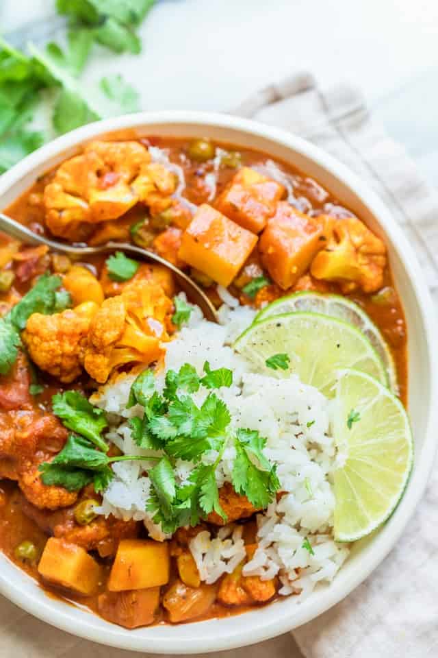 Close up of final cauliflower curry served with rice, cilantro and slices of lime