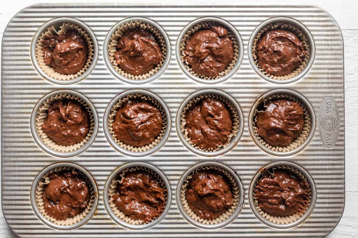 Muffin batter transfered to muffin tin lined with parchment cups