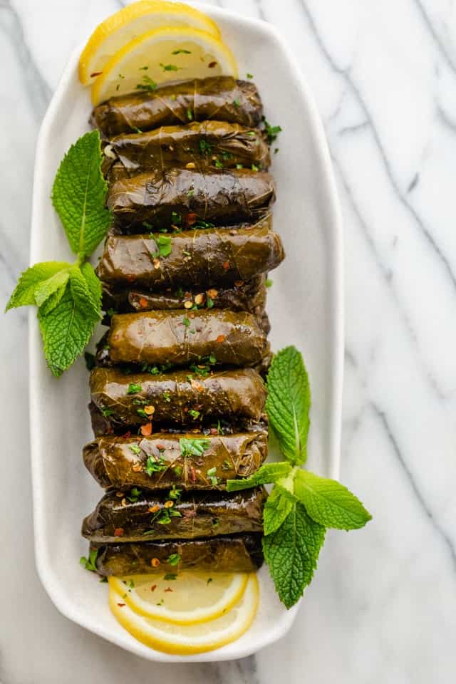 Final stuffed grape leaves lined up on a long plate