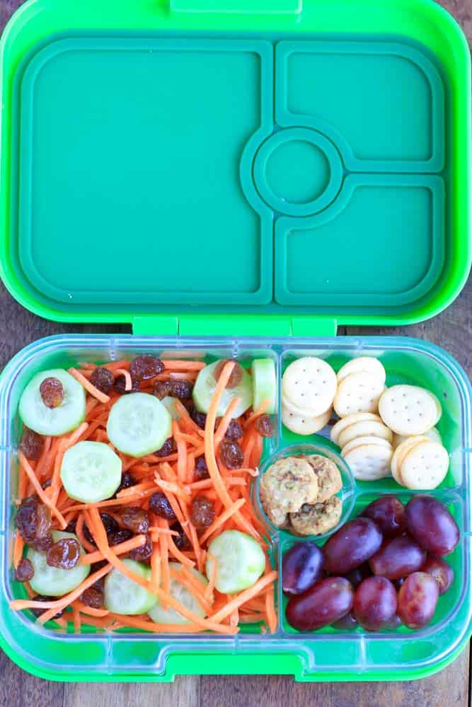 top down shot of green lunchbox containing salad and fruit