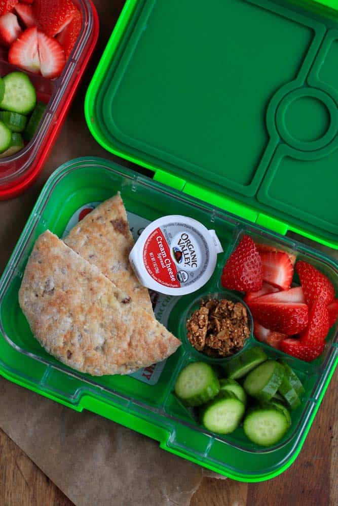 top down shot of lunch box with bread, cucumbers and strawberries
