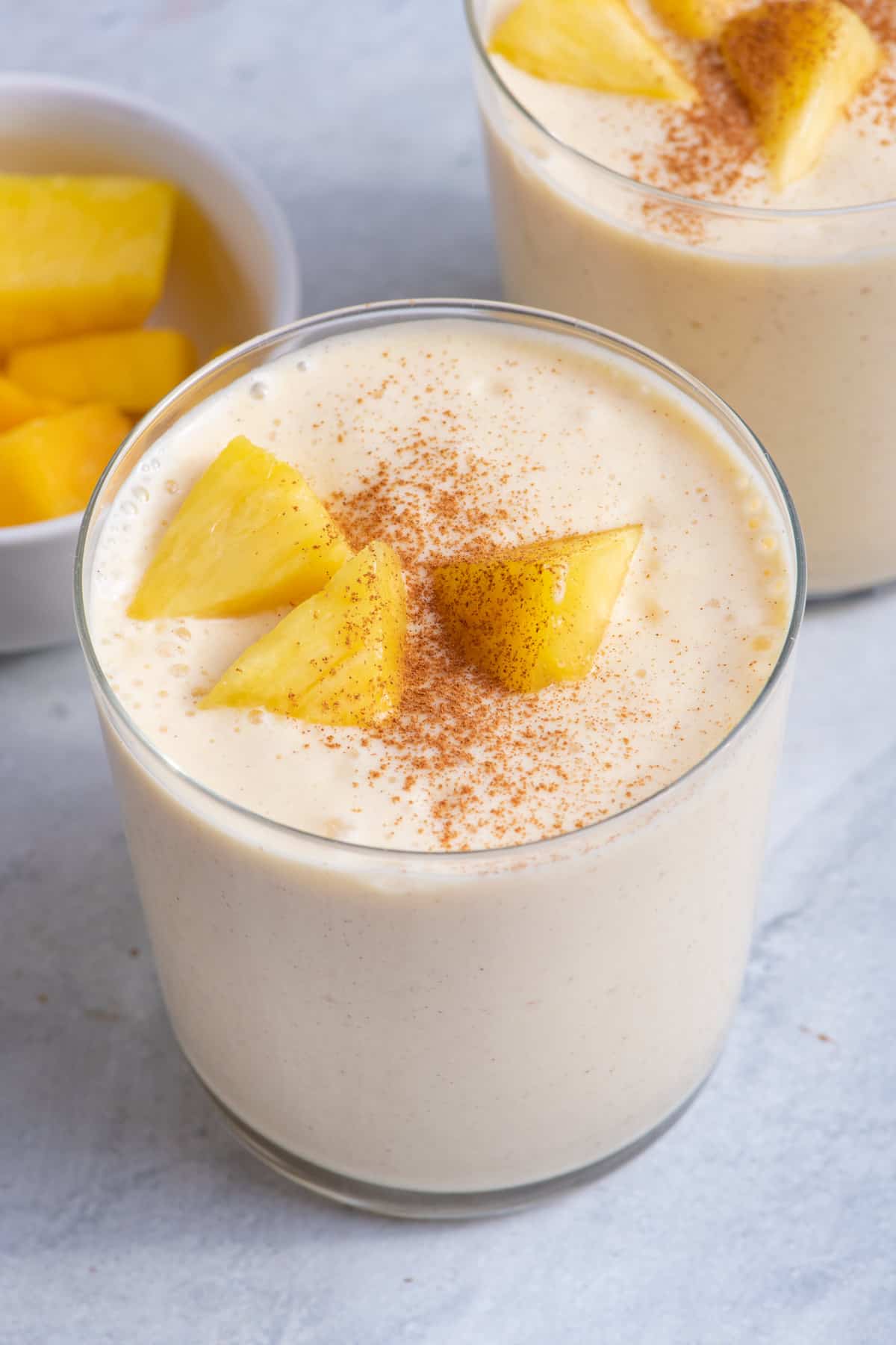 Large cup of mango pineapple smoothie with chunks of mango on top