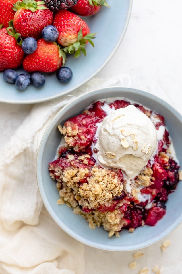 mixed berry crisp served in a bowl with ice cream