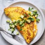 Large plate of souffle omelette topped with avocados and parsley