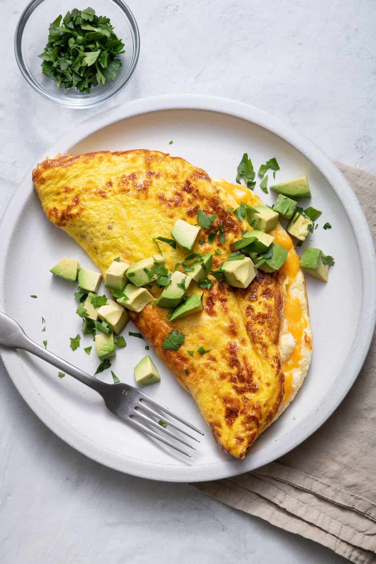 Large plate of souffle omelette topped with avocados and parsley